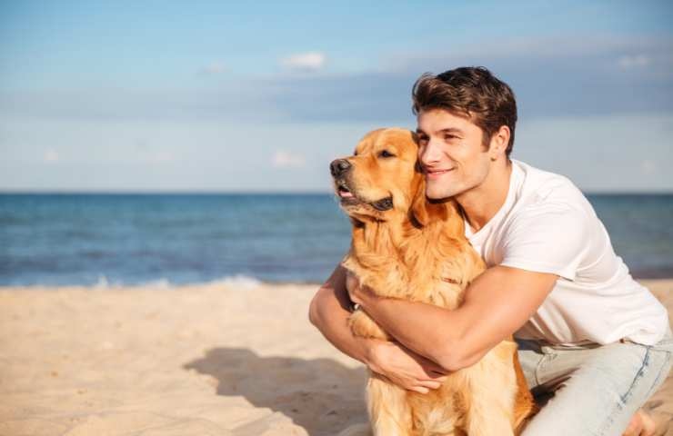 ragazzo abbraccia il suo cane in spiaggia